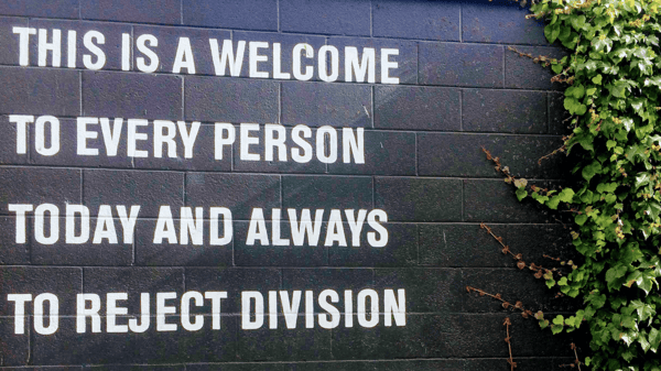 Text an einer Wand: „This is a welcome to every person today and always to reject division.”